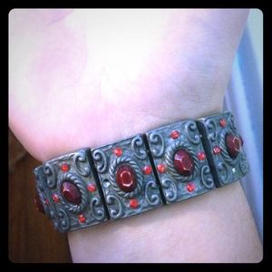 Metal bracelet with red stoned details.
