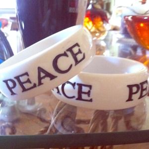 White bangle with "peace" engraved 3x around.