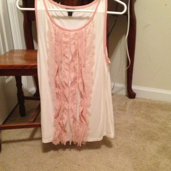 Sleeveless cream shirt with pink ruffles.
