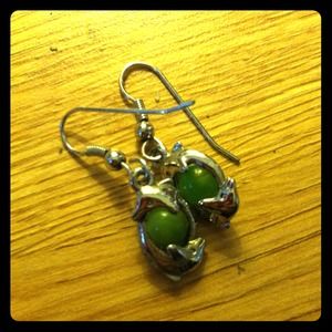 Dolphins curled around green pearl earrings.