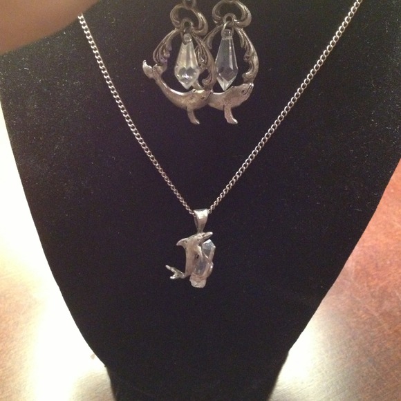 Sliver chain with dolphin holding a crystal.