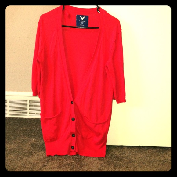 Red, long, v-neck sweater with black buttons.
