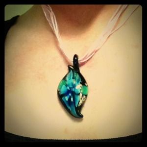 A glass necklace with a blue flower inlay
