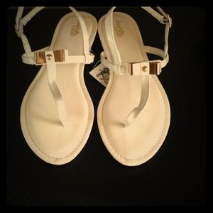 White sandals with gold bow and accents