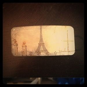 A vintage hair clip with a scene of Paris on it.