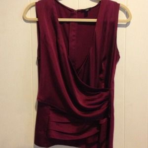 Sleeveless draped burgundy satin blouse.