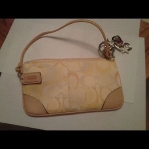 Cream colored coach wristlet with charm