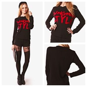 Black sweater with large red gangham style logo.
