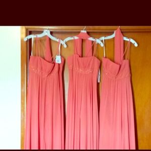 Three bridesmaid dresses w/ tags still on them.
