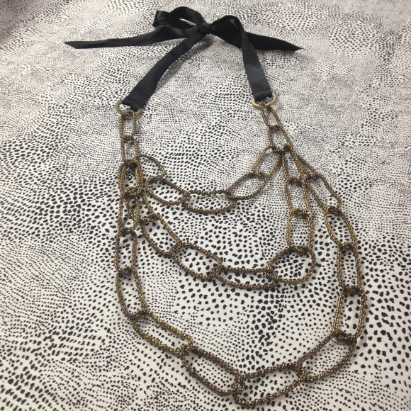 Gold metal chain necklace with blk ribbon tie.