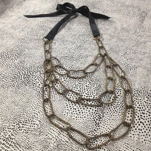 Gold metal chain necklace with blk ribbon tie.