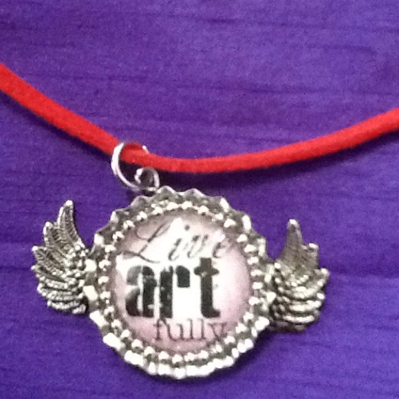 Bottle cap with wings that say "live art fully" .