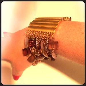 Gold color bangle with purple and green stones.