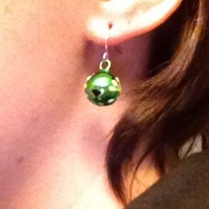 Green jingle earrings with a white snowflake.