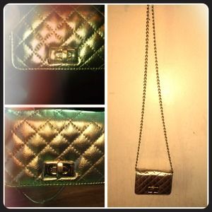 A gold quilted cross body purse with a chain strap