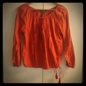 Deep reddish orange colored top with tassels.