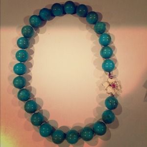 Chunky turquoise necklace with white flower clasp.