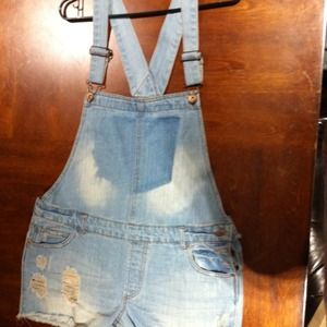 Distressed jean short overalls in a light wash.