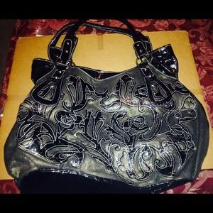 Black patten leather purse with designs.