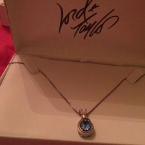 Silver necklace with gold accent and blue stone .