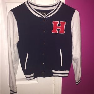 - letterman jacket with an " H " on it .