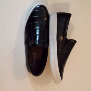 Black flat slip on sneakers.