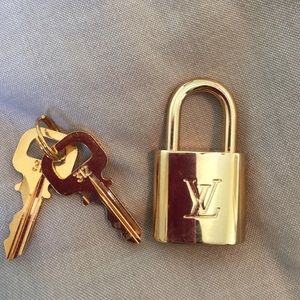 Authentic Louis Vuitton lock and key in gold.