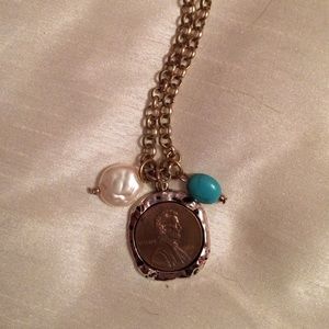 Gold necklace with penny coin and charms.
