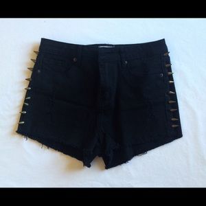 Black high rise denim shorts with brass spikes.