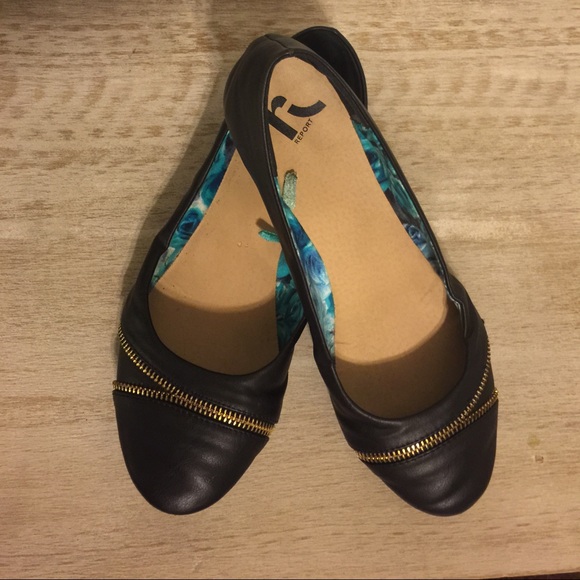 Black flats with gold zipper detail.