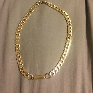 Gold chain necklace with gold bar in the middle.