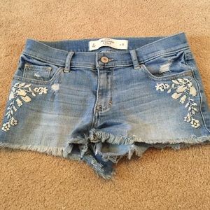 Denim short-shorts with white floral detailing.