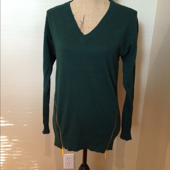 Green sweater with two decorative size zippers.