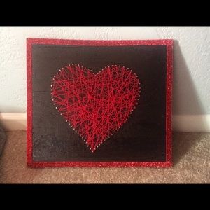 A wooden board with red string heart
