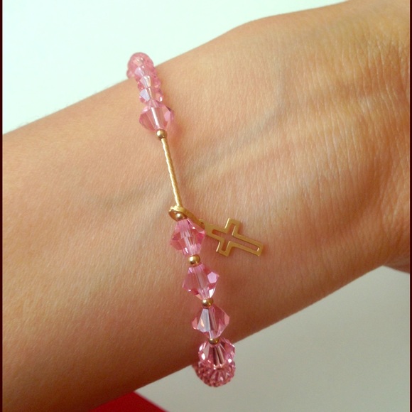 Pink bracelet with a golden cross.