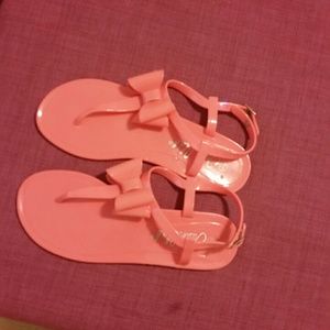 Coral plastic sandals with bow detail.