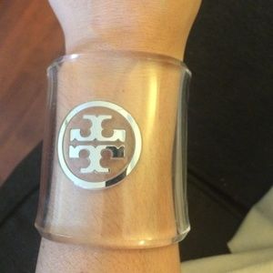 tory burch cuff in clear with silver emblem.