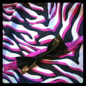 It is a pink shiny headband with a black bow