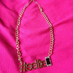 A necklace that says selfie on it