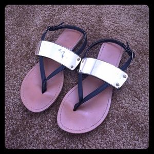Black sandals with gold band across the top