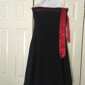 Strapless black dress with red sash and lace trim.