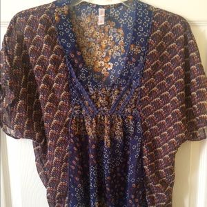 A floral blouse with a V neck pom-pom trim