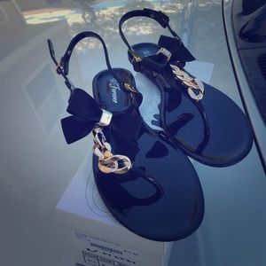 Black jelly sandals with gold bow and chain