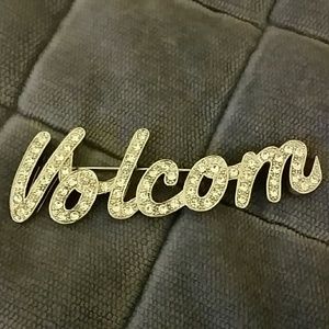 Volcom pin lined with shiny clear crystals.