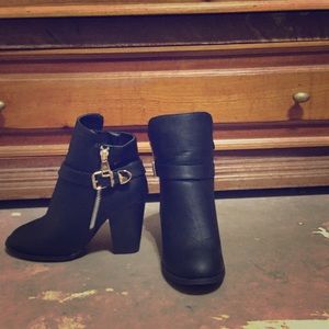 Black heeled booties with gold zipper and buckle