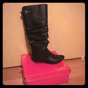 Flat black boot that goes to the knee