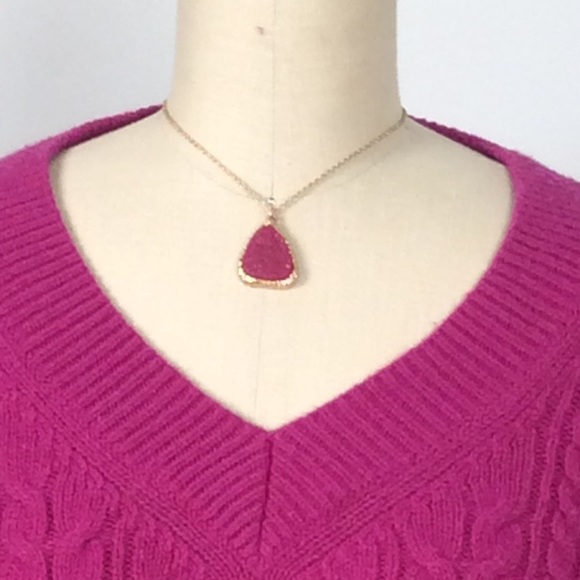Gold colored necklace with pink medallion