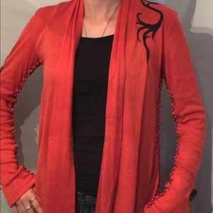 Orange cardigan with black embroidery.