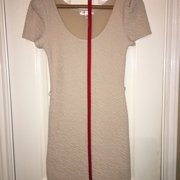Bodycon nude dress with orange belt.