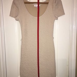 Bodycon nude dress with orange belt.